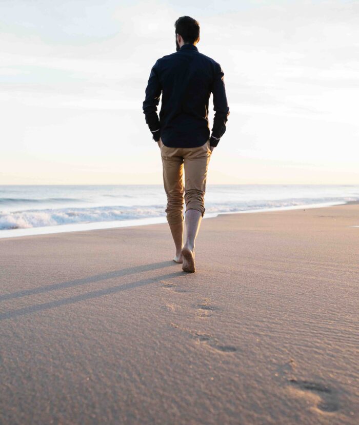Man walking on the beach, footprints in the sand showing biomechanics